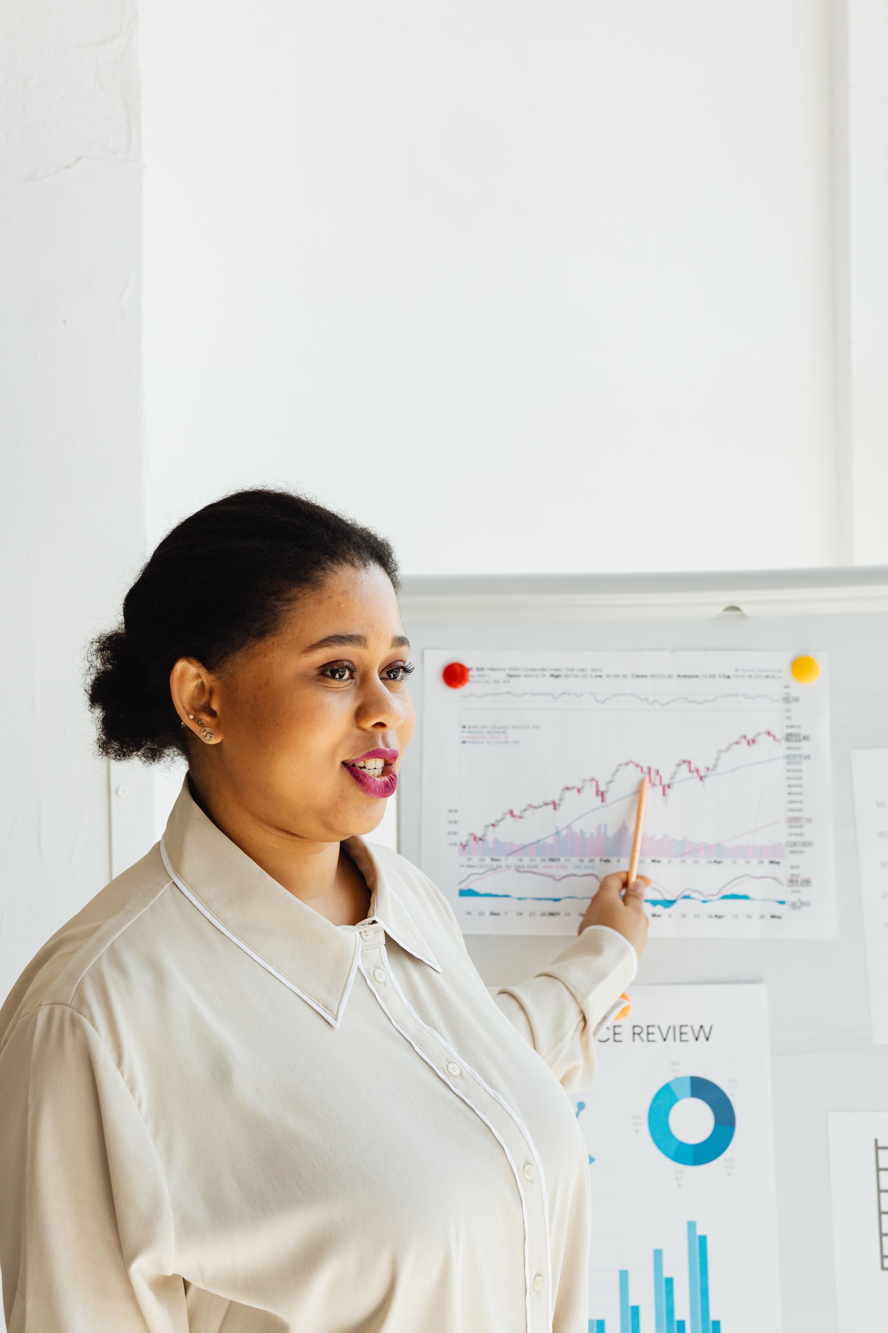 A Black presenter pointing to a chart on a whiteboard